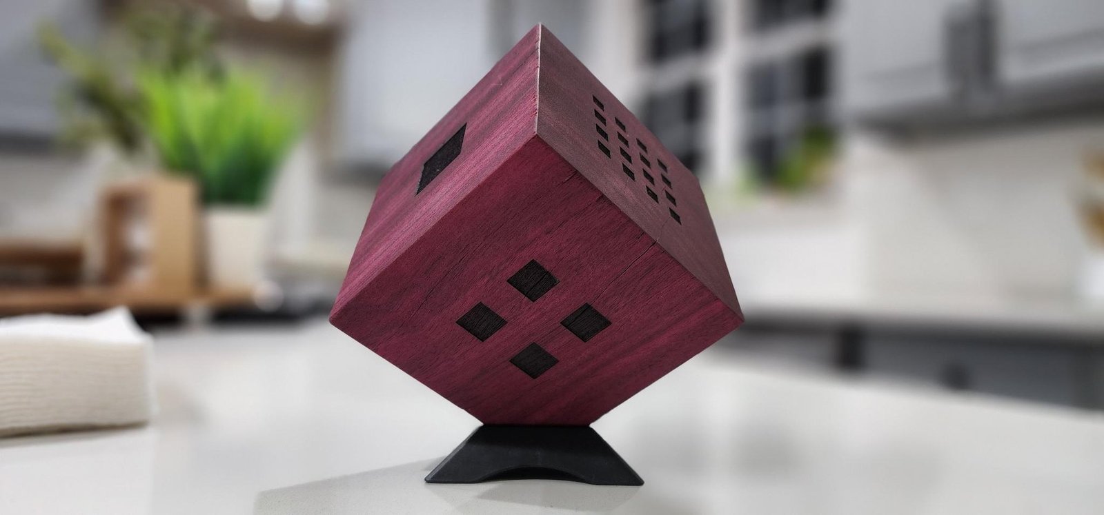 The Whole Entire Universe — finished purpleheart cube on its display stand, three faces visible, hand-engraved grids